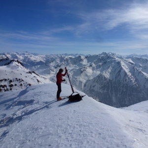 Person steht mit Skitourenski auf einem Gipfel am Staller Sattel und bereitet sich auf die Abfahrt vor. 